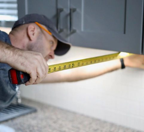contractor measuring bottoms of cabinets